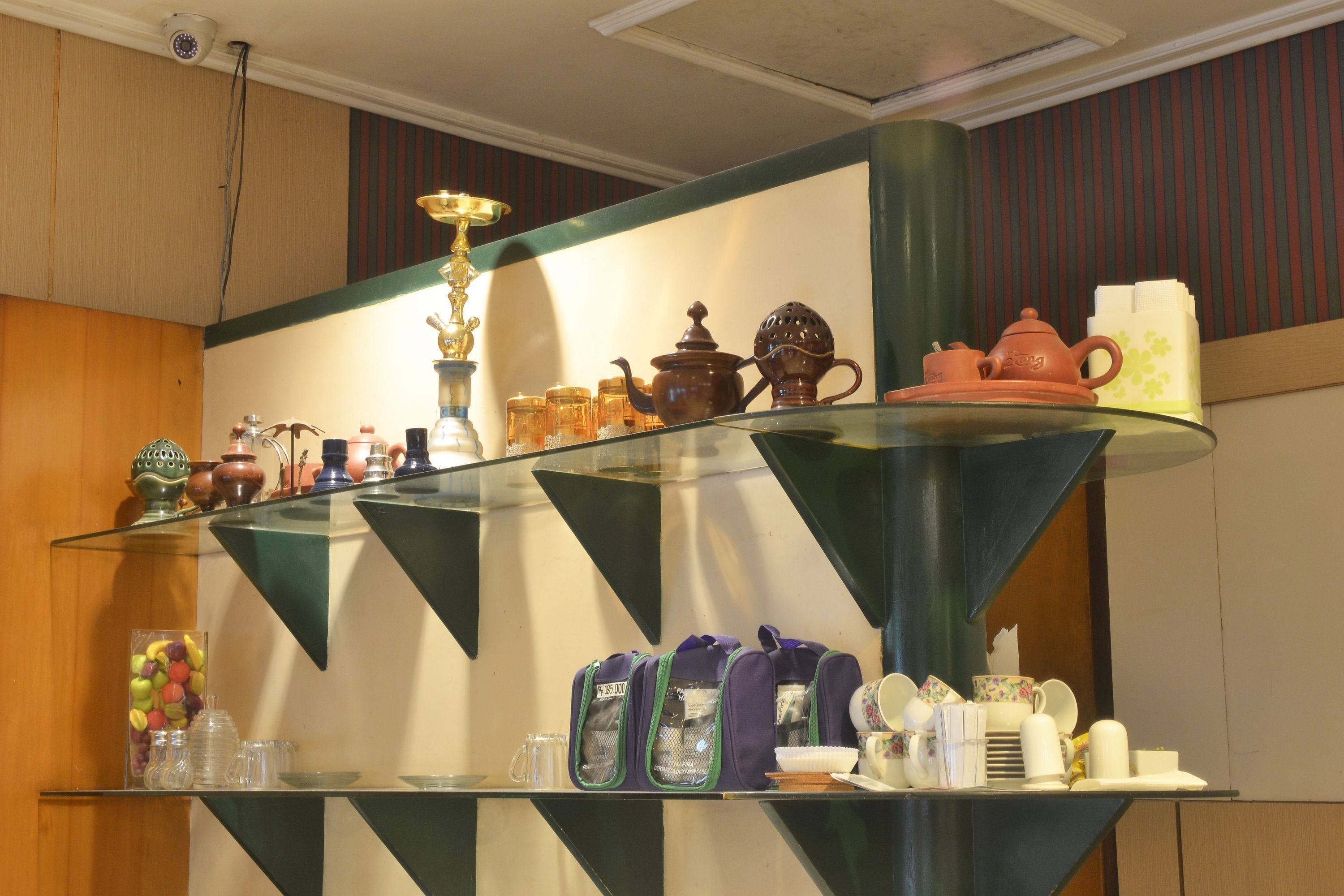 Une vitrine en verre contenant divers ustensiles de cuisine, notamment des théières, des tasses et des bocaux.