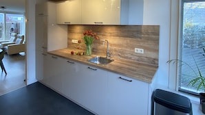 A modern kitchen with white cabinets, a wooden countertop, and a built-in sink. - Ferienhaus in die Rue Royale (Middelburg)