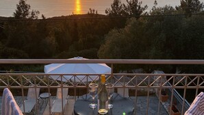 A terrace with a table, two chairs, and an umbrella. - Four bedroom villa with private pool with stunning views and beautiful sunsets (Halikeri)