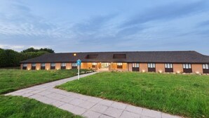 A modern building with a flat roof, multiple windows, and a paved entrance area. - Days Inn by Wyndham Sutton Scotney South (Winchester)