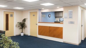 A reception area with a reception desk, a clock, and signs indicating room availability. - Days Inn by Wyndham Sutton Scotney South (Winchester)