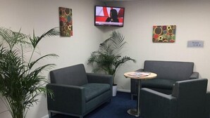 A waiting area with two sofas, a small table, and a TV on the wall. - Days Inn by Wyndham Sutton Scotney South (Winchester)