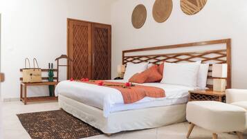 A neatly arranged bedroom with a bed, bedside tables, a chair, a wardrobe, and decorative wall art.