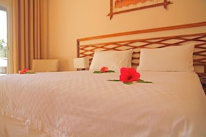 Una habitación de hotel con una cama, dos almohadas, una mesita de noche y una ventana con cortinas.