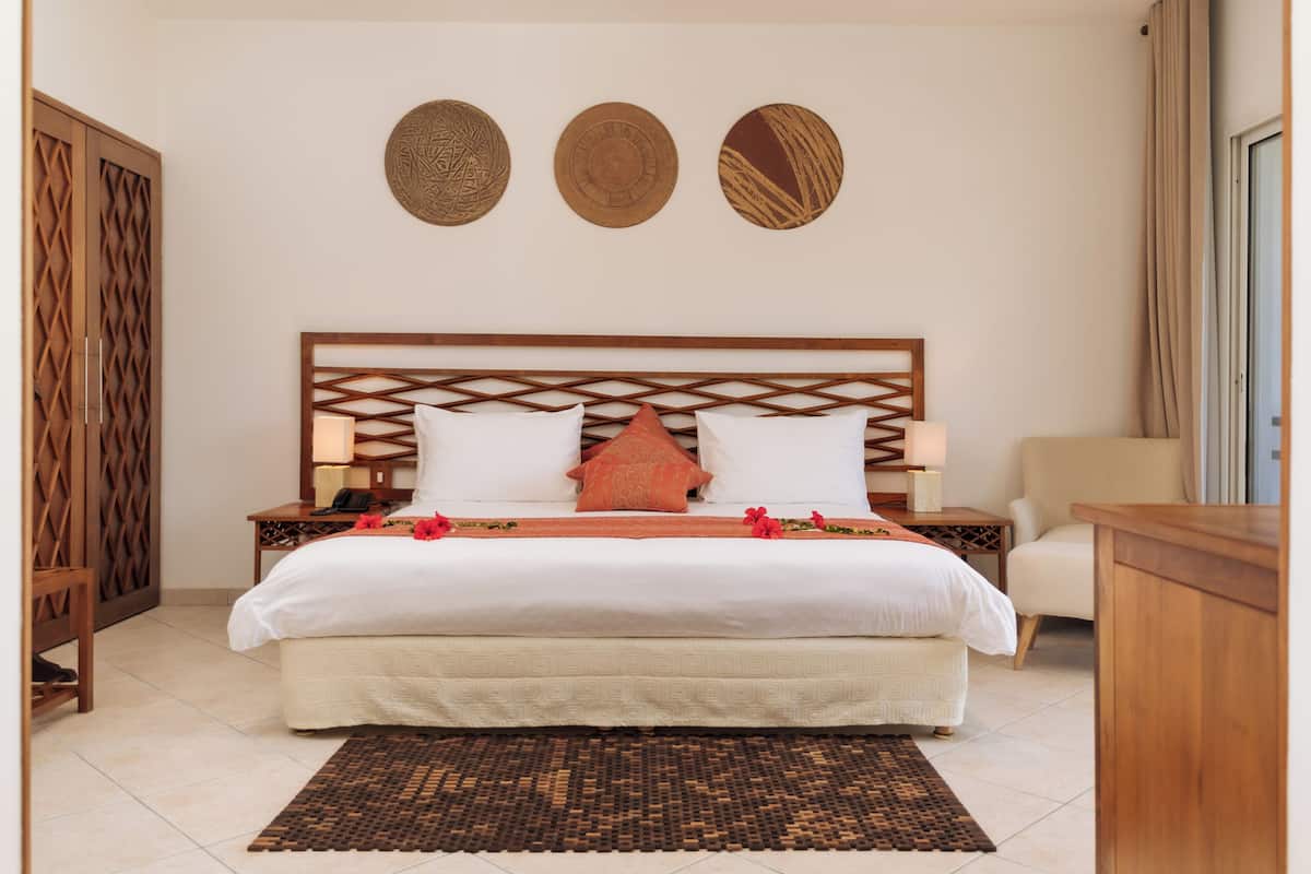 Una camera da letto ordinata con un letto, comodini, una sedia e decorazioni murali.