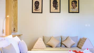 A room with a sofa, pillows, and framed artwork on the wall.