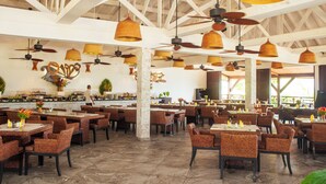 Un restaurante espacioso con techos altos, mobiliario de mimbre e iluminación colgante.