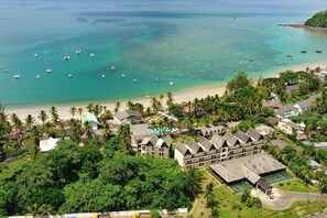 Ein Resort mit mehreren Gebäuden, einem Strand und Booten im Wasser.