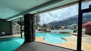 Una piscina interior moderna con un suelo de madera y un pilar de piedra.