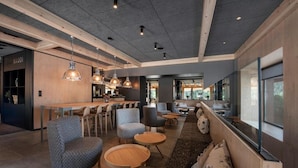 Um interior moderno com área de bar, assentos e vista através de grandes janelas.