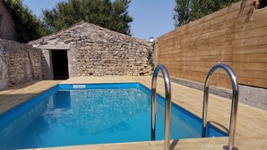Piscina con bordo in legno e ringhiere in metallo.