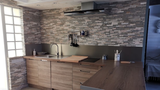 Una cucina moderna con schienale in pietra, mobili in legno e una grande isola con lavello.