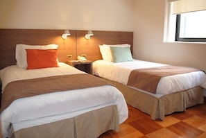 Two single beds with wooden headboards, bedside lamps, and a window with blinds. - Hotel Santa Lucia (Santiago)