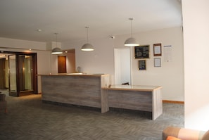 Welcome to our reception area, featuring a central desk with pendant lights and a herringbone-patterned floor.