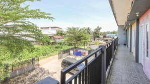 Ein Balkon mit Blick auf eine Wohngegend, ein parkendes Auto und einen Zaun.