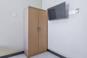 Ein Zimmer mit Holzschrank, flachbildfernseher an der Wand und Steckdose.