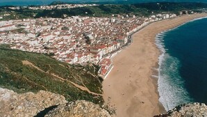 Un paysage urbain côtier avec une plage, des bâtiments et un arrière-plan vallonné.