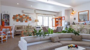 Un salon moderne avec un canapé beige, une table basse blanche et une bibliothèque.