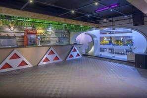 A bar area with a Coca-Cola refrigerator, shelves with bottles, and a seating area with tables and chairs. - The Fern Residency Yeshwanthpur (Bengaluru)