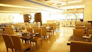 A spacious dining area with multiple tables and chairs, a large screen displaying a map, and a clock on the wall. - The Fern Residency Yeshwanthpur (Bengaluru)