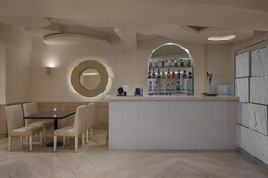 A modern bar area with a round mirror, a counter with bottles, and a seating area with chairs. - The Fern Residency Yeshwanthpur (Bengaluru)