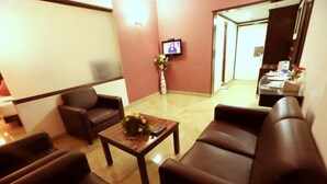 A hotel lobby with leather sofas, a wooden coffee table, a television on the wall, and a reception desk in the background. - The Fern Residency Yeshwanthpur (Bengaluru)