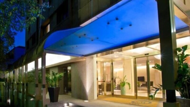 Ein Hotel mit Glastür, überdachtem Zugang und Topfpflanzen.