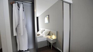 Une chambre d’hôtel avec un lit, une table de chevet et un peignoir suspendu à un porte-manteau.