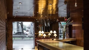 Un vestíbulo de hotel con una recepción pulida, iluminación empotrada y vistas a la calle.
