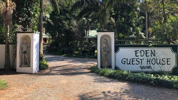 La entrada a Eden Guest House rodeada de vegetación tropical.