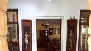 Un pasillo con piso de baldosas, obras de arte en las paredes y un felpudo en la entrada.