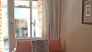 Un dormitorio con cama, almohadas, ventilador de techo y ventana con cortinas.