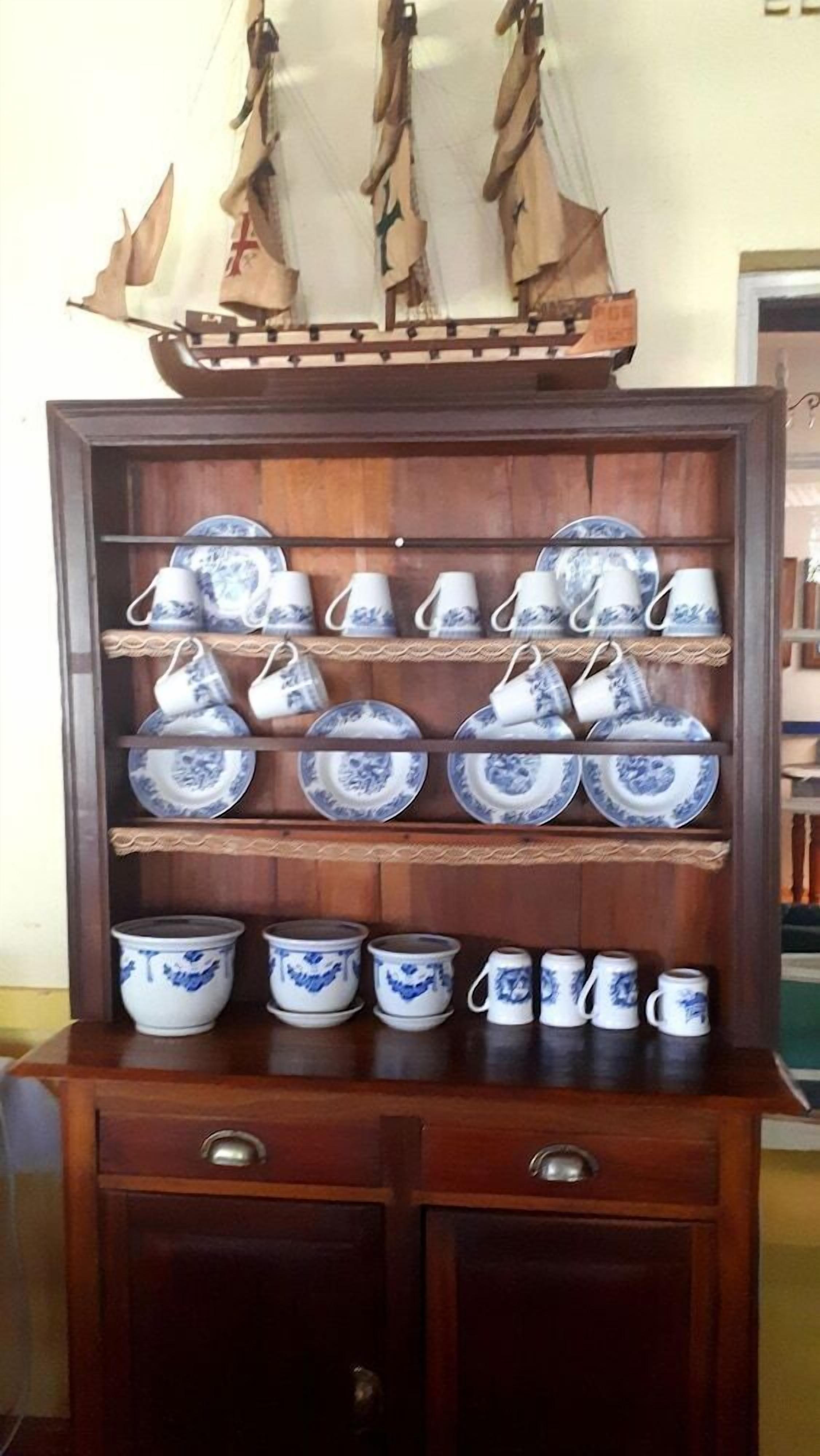 A wooden display cabinet with shelves holding blue and white patterned plates, cups, and bowls.