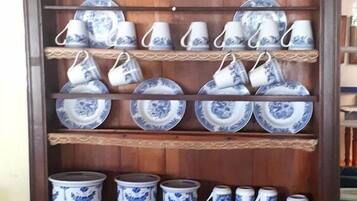 A wooden display cabinet with shelves holding blue and white patterned plates, cups, and bowls.