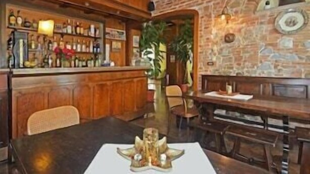 A bar area with wooden furniture and a stone wall. There is a table with a decorative centerpiece and a bench. - Garden (Viareggio)