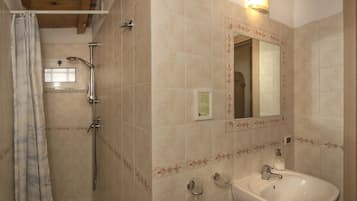 A bathroom with a shower, a sink, and a mirror.