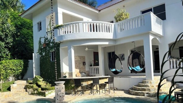 A two-story house with a swimming pool, outdoor seating, and a covered patio area. - Pool Jacuzzi & Tropical Oasis Yard With Fruit Trees (Sosua)