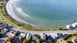 An aerial view of a coastal residential area with houses, a beach, and a road. - The Blue Pearl (Nahant)