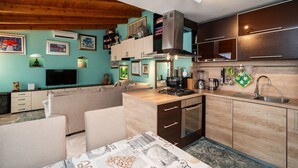 Une cuisine moderne dotée d’un îlot central, d’appareils électroménagers intégrés et d’un coin repas avec un canapé et une table.