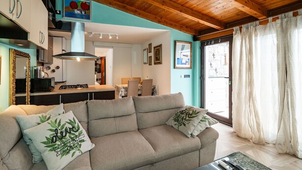 Un salon chaleureux avec un canapé beige, une table basse et un coin cuisine à l’arrière-plan.
