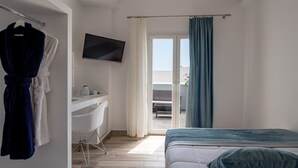 A hotel room with a bed, a desk, a TV, and a balcony with a view. - Oasis Hotel Fira (Santorini)