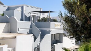 A modern building with a staircase, a reception area, and a sign with palm tree logo. - Oasis Hotel Fira (Santorini)