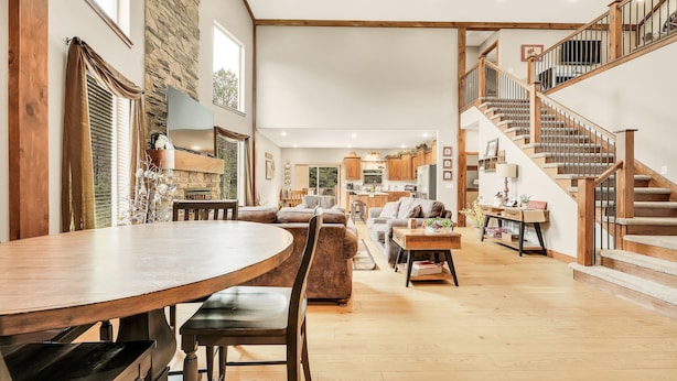 A spacious living area with a wooden dining table, sofas, and a staircase with wooden railings. - Family Style 6 Bedroom Home, 2 Pools, New Patio Furniture!  Clean & Relaxing! (Hollister)
