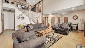 A spacious living area with a staircase, two sofas, a coffee table, and a dining table. - Family Style 6 Bedroom Home, 2 Pools, New Patio Furniture!  Clean & Relaxing! (Hollister)