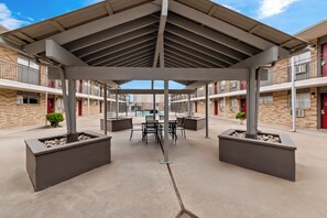 Un espacio al aire libre techado con piscina, mobiliario y vistas del edificio.