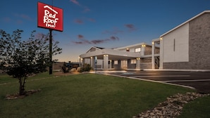 A Red Roof Inn with a modern building, a parking lot, and a well-maintained lawn.