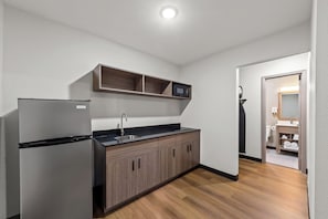 A modern kitchen with a refrigerator, sink, and wooden cabinets. - Red Roof Inn Del Rio (Del Rio)