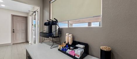 A kitchen area with a countertop displaying various items, a window with a blind, and a door leading to another room.