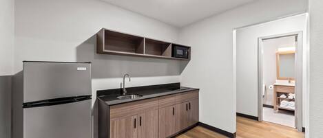 A compact kitchen with a refrigerator, a sink, and a microwave.