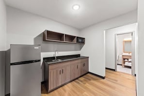A compact kitchen with a refrigerator, a sink, and a microwave.